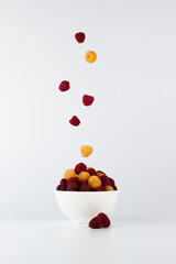 Raspberries in a white bowl. Levitation. Raspberry parachuting over a berry.