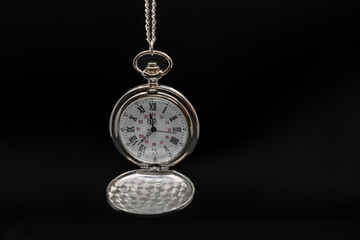 An old pocket watch on black background, copy space