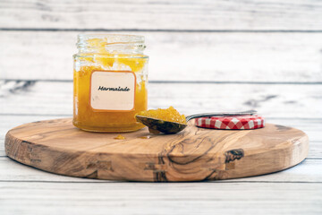 Homemade marmalade jam with a spoon on a wooden plate, copy space