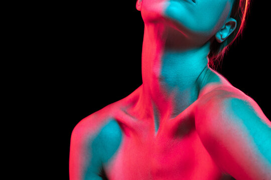 Close up female neck, collarbones and shoulders in red neon light over dark background. Natural beauty, fitness, diet, spa, aesthetic cosmetology