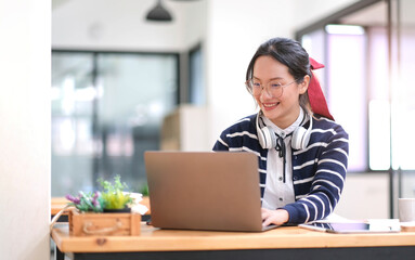 Student learning on laptop indoors- educational course or training, seminar, education online concept, Asian woman with modern laptop and headphones learning at home