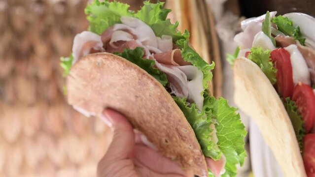 Spianata Sarda. Typical tortilla bread in italy Sardinia region. Baking bread Thin round with different flour. High quality footage. Piadina with prosciutto crudo, green salad, tomatoes and cheese. 