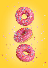 Three sweet pink donuts are flying in the air. Yellow background.