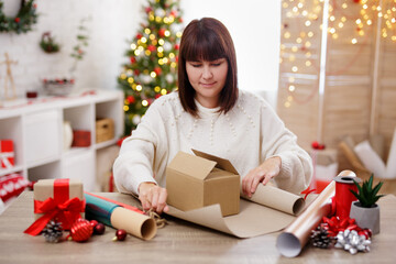 Woman wrapping the christmas gift in decorated room