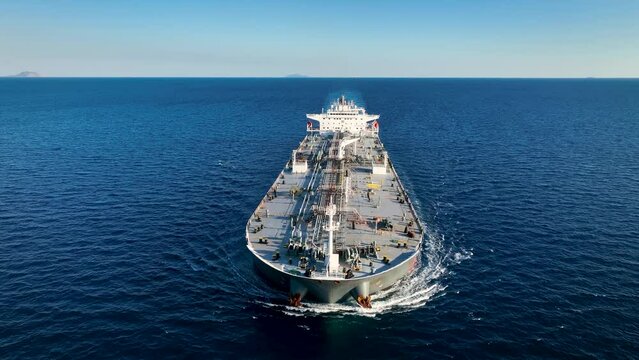 Aerial front view of a heavy loaded oil tanker ship travelling over blue ocean with speed