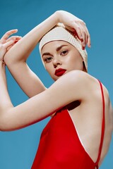 A professional model in a retro-style swimming cap in a red swimsuit poses with her hands near her...