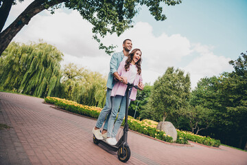 Photo of sweet excited two people together wear casual shirts driving eco scooter smiling outside garden © deagreez