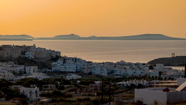 Day to night time lapse view of the cityscape of Naxos island town, withe the castle, harbour and famous Portara gate, Cyclades, Greece