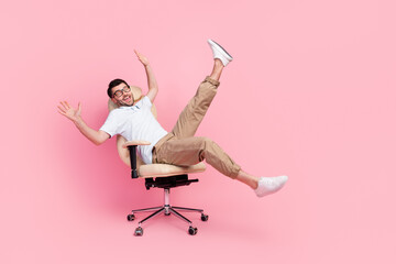 Full size photo of playful guy manager fooling ride fast cozy office chair isolated on pastel color...