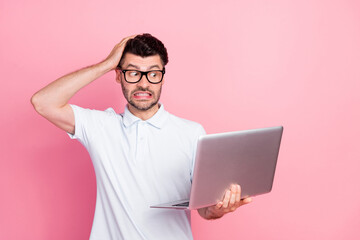 Photo of astonished worried man hand touch head guilty stupor something wrong netbook empty space isolated on pink color background