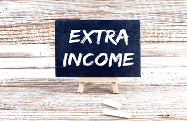 EXTRA INCOME text on the Miniature chalkboard on wooden background
