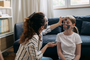 Fototapeta premium mother and daughter applying cosmetic face mask at home