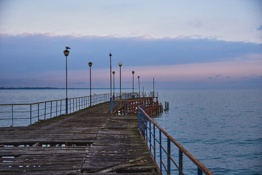 A pier stretching far into the sea against the backdrop of a beautiful sunset.