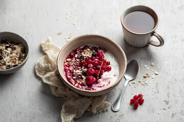 petit déjeuner bol de yaourt muesli, fruits secs, groseilles et framboises sur table