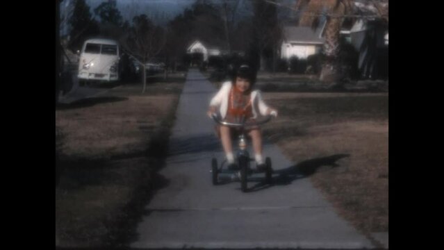 Riding on the Sidewalk 1966 - Girls ride a tricycle and a bicycle on a sidewalk in Canoga Park, California in 1966.