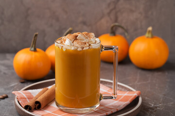 Autumn pumpkin spice latte with cream in mug and mini pumpkins on dark table. Traditional Coffee Drink for Autumn Holidays. Harvest Festival, Happy Thanksgiving. Fall time. Home comfort.