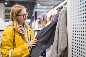 Young pretty blonde woman customer shopping at textile department and choosing towels at home goods store. 