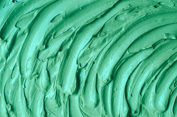 Green cosmetic clay (alginate facial mask) texture close up. Abstract background with brush strokes.