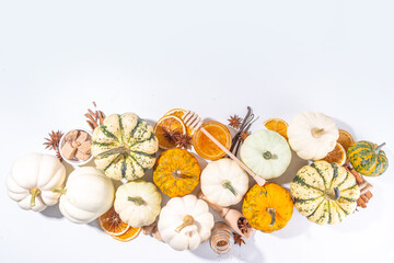 Autumn fall pumpkin spice baking and drink ingredients. Various colorful pumpkins, nuts, seasonal spices on white background. Cooking pumpkin pie, latte, cookies for autumn Thanksgiving holidays