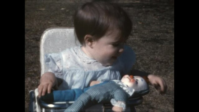 Baby and Doll 1965 - A child sits in a bouncy seat as her mother offers her a doll, in Canoga Park, California in 1965. 
