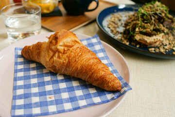 Fresh croissant on bleu and white checkered napkin in bistro