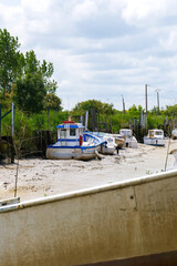 Fototapeta na wymiar Boats on dry land during low tide in small inland port in estuary of Gironde, France
