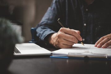 Hand holding pen writing paperwork business document financial investment or signature contract job...