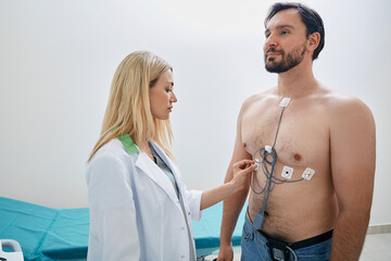 Man using Holter with ECG sensors to monitor his heart health under supervision of licensed cardiologist - obrazy, fototapety, plakaty