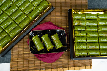 Wrapped pistachio baklava is placed on a serving plate. Look from above