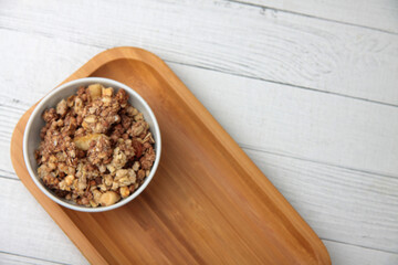 a bowl of granola on wooden tray on wooden table flat lay