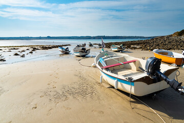 The famous beach of Kersiguenou, Brittany, France, during low tide. Old boats in the foreground. Atlantic ocean with blue sky on the background.