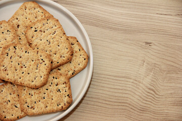 dry square diet crackers with black cumin seeds and quinoa on a decorative glass plate