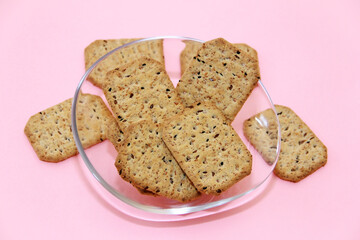 dry square diet crackers with black cumin seeds and quinoa on a decorative glass plate