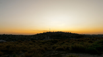 Pôr do sol ao entardecer com céu laranjado limpo, em pedreira no bairro Industrial, Contagem, Minas Gerais.