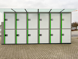 New green and white bicycle box station at a train station to protect bicycles from damage and theft