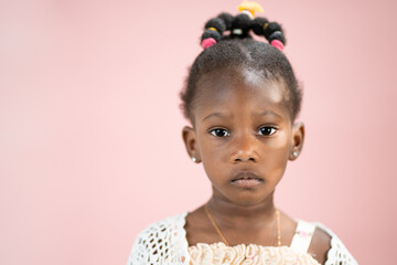Fototapeta premium Ritratto di una piccola ragazza bella afroamericana isolata con lo sfondo rosa 