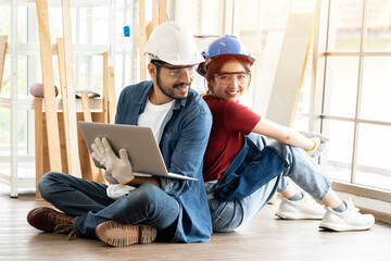 Happy male carpenter and female carpenter working using laptop computer design furniture in the wood workshop