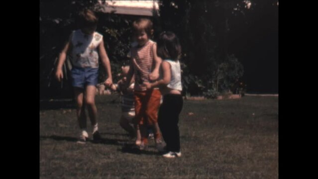 Walking With Brother 1964 - Siblings hold hands and help their younger brother as he learns to walk in Canoga Park, California in 1964. 