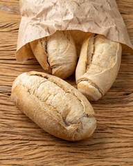 Whole grain french bread, salt bread or pistolet on a paper bag over wooden table