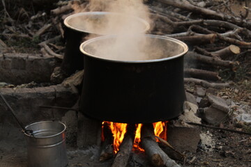 An old black aluminum pot boiling on natural fireplace