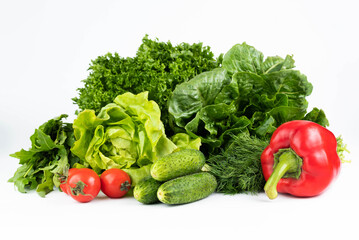 On a white background, tomatoes, cucumbers, red peppers, dill, different varieties of green salad.