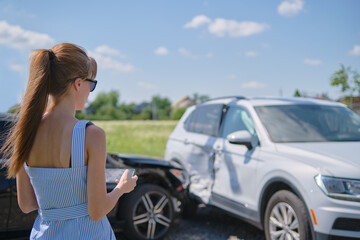 Stressed woman driver standing on street side shocked after car accident. Road safety and insurance concept