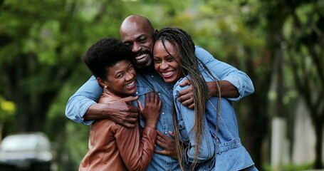 Fototapeta premium Three Friends hugging each other. African man and women embrace smiling