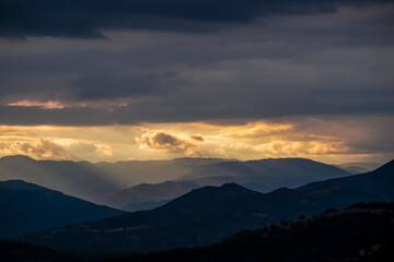 Panoramic view during sunset from Meteora rocks to Pindos mountains, the biggest mountain range of Greece, Thessaly district, Greece, Europe. Soft sun beam through clouds reaching the summit tops
