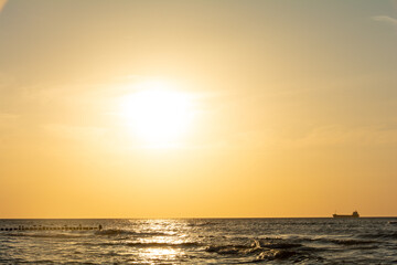 Fototapeta na wymiar Sunset over the sea with a ship on the horizon
