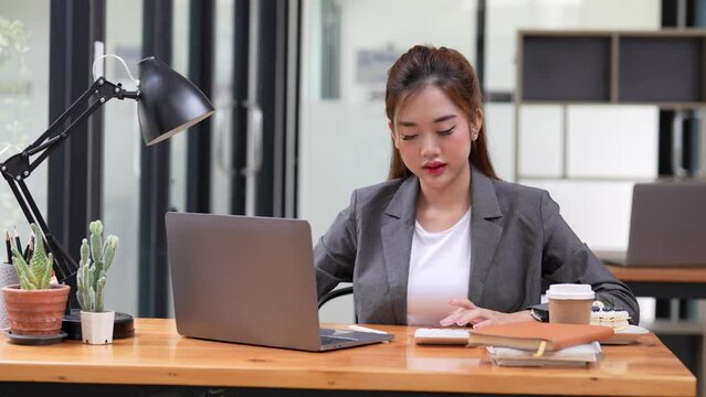 female accountant using calculator and laptop computer at her office