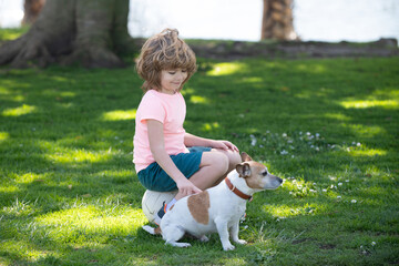 Kid caress dog. Child boy with dog walking outdoor. Kid playing with puppy. Children with pet...