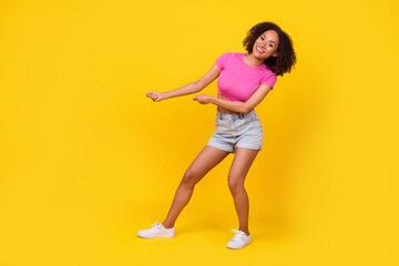 Fototapeta na wymiar Full length profile photo of funky carefree girl hands pull empty space rope isolated on yellow color background