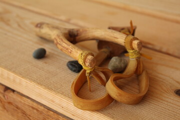 A wooden craft slingshot with some rocks and pebbles