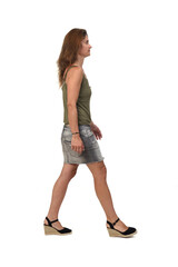 side view of a  woman with denim skirt and spadrille walking  on white background